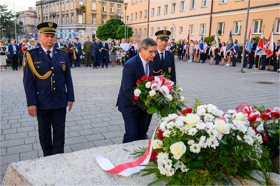 Prezydent Roman Ciepiela w asyście strażników miejskich składa kwiaty przed Pomnikiem Ofiar Stalinizmu